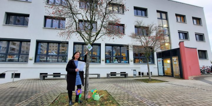 Frau steht vor Baum bei der Stadtteilbibliothek Lobeda Baumpatenschaft Jena
