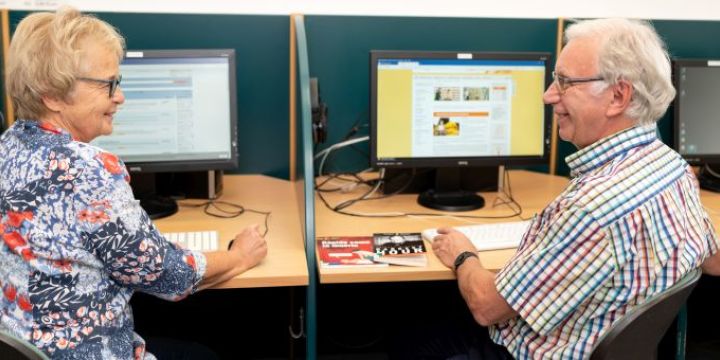 Ein Mann und eine Frau sitzen vor zwei Computern