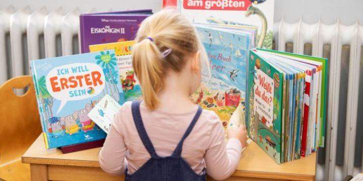 Mädchen steht vor Büchertisch