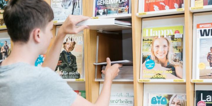 Junge vor Zitschriftenregal Press reader EAB Jena