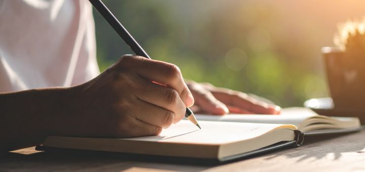 Mann schreibt in ein Buch