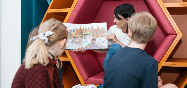 Dunkelhaarige Frau liest Kindern vor