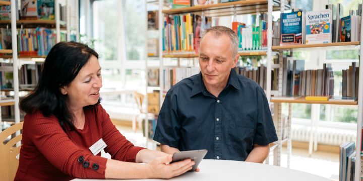 Eine frau hat einen E-Reader in der Hand und erklärt diesen einen Mann.  ©JenaKultur | C. Worsch