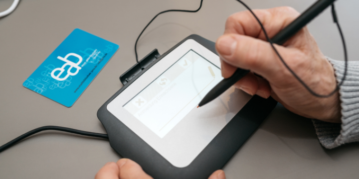 Frau unterschreibt auf einem digitalen Unterschrifts-Pad