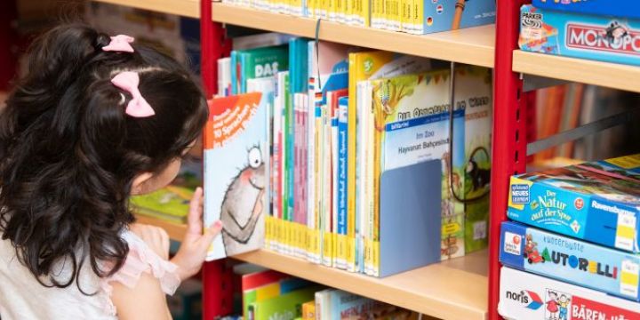 Ein Mädchen sucht am Regal Bücher raus.   ©JenaKultur | C. Worsch 