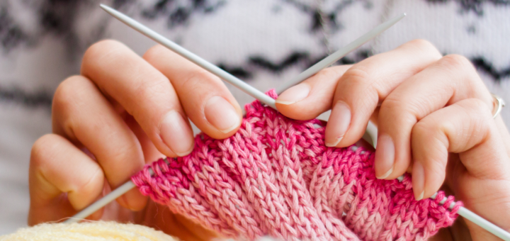 Eine Frau strickt mit rosa Wolle