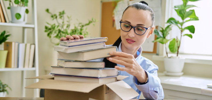 Frau packt Bücher aus einem Karton