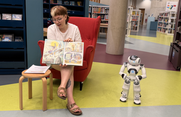 Frau liest vor, daneben steht ein Roboter